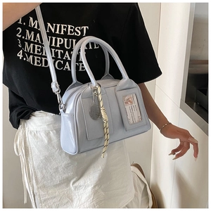 Close-up of light blue patent leather crossbody bag with charms and adjustable strap