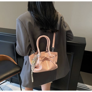 Detailansicht der rosa Lackleder-Beuteltasche mit Schleife und gestreiftem Anhänger