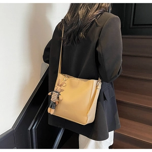 Détail du sac seau en cuir kaki avec logo Mengxi et breloque lapin sur la bandoulière