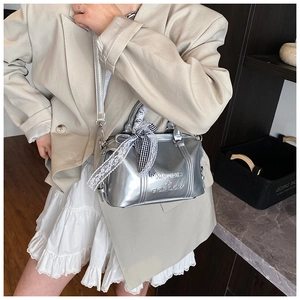 Close-up of silver pillow bag featuring lace ribbon bow and embossed brand logo