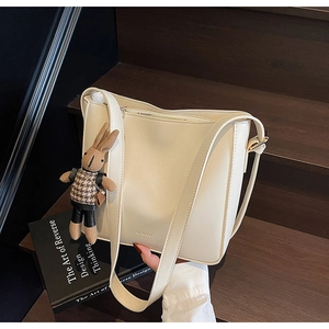 Détail du sac seau crème avec logo WWTU et charm lapin mignon sur un escalier en bois