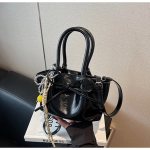 Detail der schwarzen Lackleder-Beuteltasche mit großer Schleife und Perlenanhänger