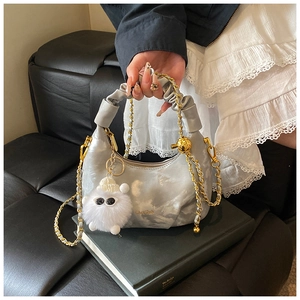 Détail du sac plissé argenté avec chaîne dorée et breloque petit monstre en peluche