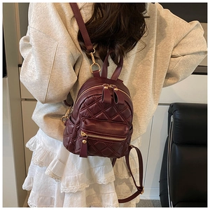 Detail eines weinroten gesteppten Mini-Rucksacks mit goldfarbenen Reißverschlüssen