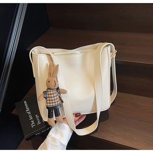 Détail d'un sac seau en cuir PU crème avec fermeture éclair et breloque lapin mignonne