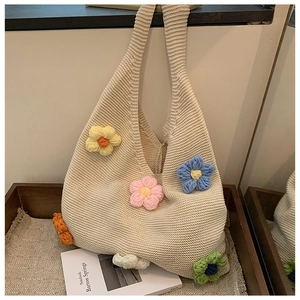 Detailed macro shot of 3D colorful crochet flowers on a beige knit tote bag texture