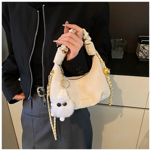 Detail of cream pleated handbag with golden chain and cute plush monster charm