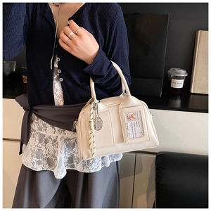 Detail of cream leather handbag with transparent card slot and metal racket charm