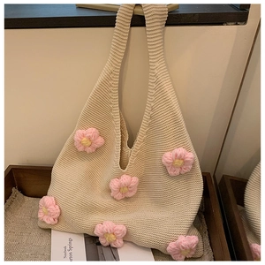 Detailed macro view of cream knitted tote bag featuring 3D pink floral crochet accents