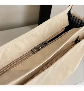 Detail view of smooth dual zippers and multi-layer internal compartments of beige tote bag
