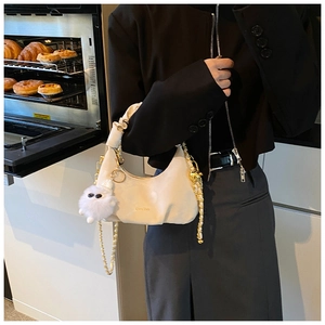 Détail du sac à main plissé blanc cassé avec chaîne dorée et breloque peluche
