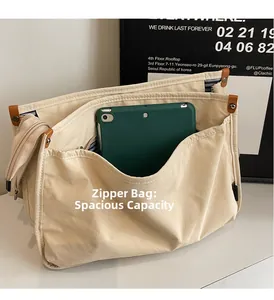 Detail view of large beige canvas tote bag showing striped lining and zipper pocket