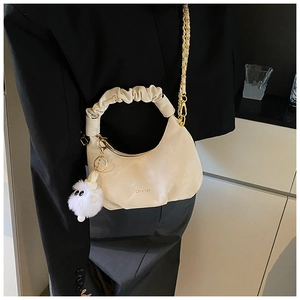 Détail du sac croissant plissé blanc cassé avec chaîne dorée et pompon en fourrure