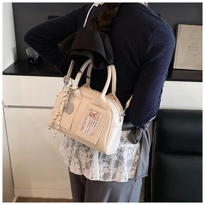 Detail of cream leather handbag with tennis racket charm and lace trim decoration