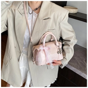 Detail of pink Boston bag featuring embossed MAJOR NEW YORK text and lace bow charm