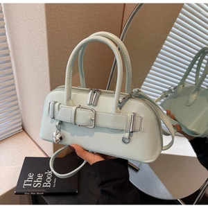 Détail du sac bandoulière vert menthe avec boucle décorative et pendentif en forme de cœur