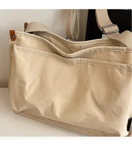 Detail of adjustable strap and multi-pocket design on beige canvas tote bag