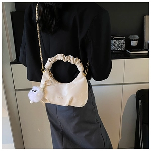 Mannequin portant un sac hobo plissé avec chaîne dorée et pompon duveteux