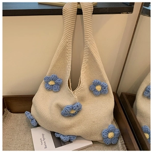 Detailed knit texture and 3D blue floral crochet accents on the beige tote bag