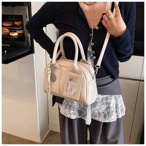 Cream-colored crossbody bag featuring clear card slot and tennis racket charm accessory