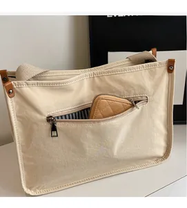 Detail of canvas tote bag showing front zipper pocket and striped interior lining