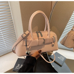 Détail du sac bowling en cuir verni rose clair avec breloque cœur argentée et boucles métal