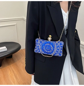 Détail de la pochette de soirée bleue avec motif fleur en strass et chaîne dorée chic