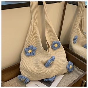 Detail of handmade knit tote bag featuring 3D blue and yellow floral crochet patterns