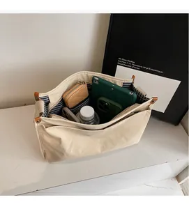 Interior detail of beige canvas tote bag with multiple compartments and striped lining