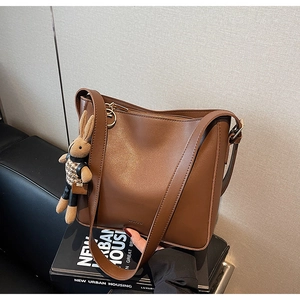 Détail d'un sac seau en similicuir marron mat avec un joli pendentif de poupée lapin