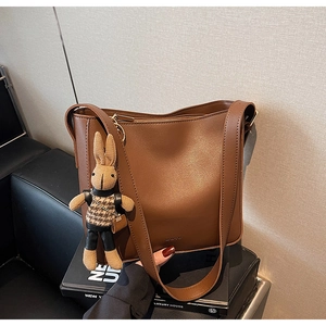 Gros plan du sac seau en cuir mat marron avec charmant pendentif lapin en tricot attaché