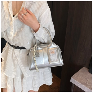 Detail of silver metallic handbag with clear card slot and woven rope accessory detail