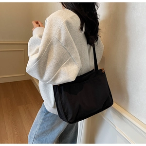 Detail showing black canvas tote bag with brown leather accents on casual model
