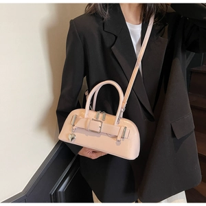 Sac bowling chic en cuir verni rose pâle avec breloque cœur porté par un mannequin