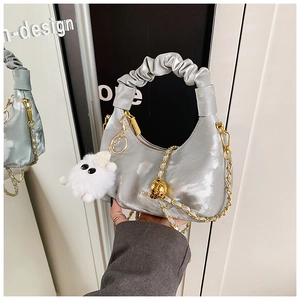 Détail du sac croissant argenté avec poignée plissée et breloque en peluche