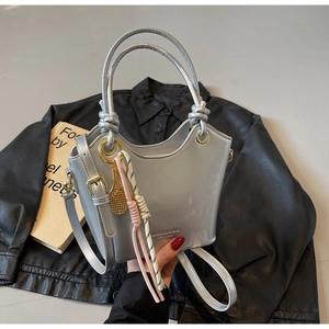 Detalle de bolso saco plateado con colgante de raqueta y acabado metálico brillante