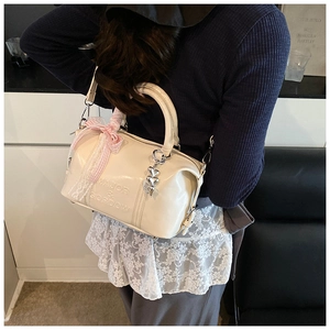Detailed back view of a cream Boston bag with plaid bow and heart charm on a model