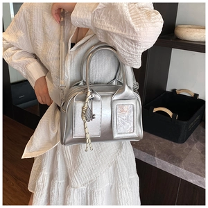 Detail of silver metallic handbag with dual handles and transparent card pocket feature