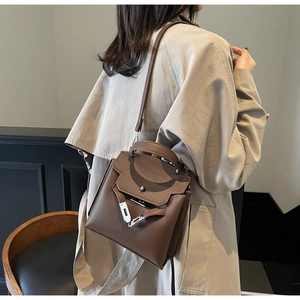 Braune Handtasche aus Leder mit Litschimuster, getragen zu einem beigen Trenchcoat