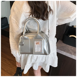 Detailed shot of silver Boston bag with clear card slot and tennis racket charm accessory