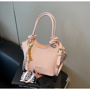 Detalle de bolso cubo de cuero encerado rosa con asa anudada y herrajes de aro dorado