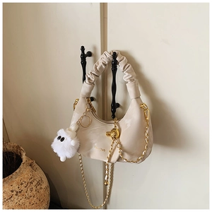 Détail du sac hobo plissé beige avec chaîne dorée et accessoire de charme fantôme en peluche