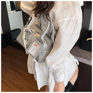 Detail of silver metallic pillow bag featuring a clear card slot and rope tassel ornament