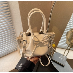 Detail einer beigen Falten-Beuteltasche mit Schleife und silbernem Perlenanhänger-Dekor