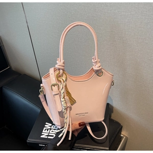 Detalle de bolso cubo de charol rosa brillante con asa de nudo y colgante de borla