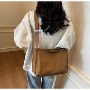 Brown canvas crossbody bag with wide adjustable strap shown from a back-view perspective