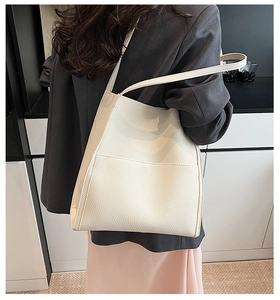 Close-up of cream white tote bag with lychee grain texture shown on model shoulder