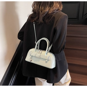 Sac à main en cuir vert menthe avec boucle métallique et breloque cœur porté par un mannequin