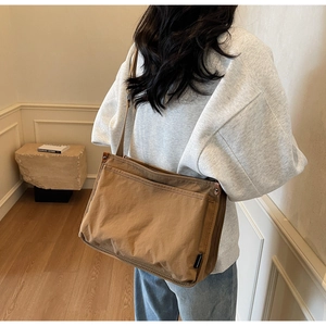Detail of a brown canvas messenger bag showing front pocket and durable snap button