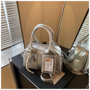 Detail of silver metallic Boston bag featuring removable strap and tennis racket charm